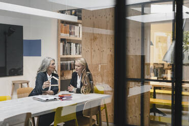 Mature and young businesswoman examining architectural model in loft office - GUSF03405