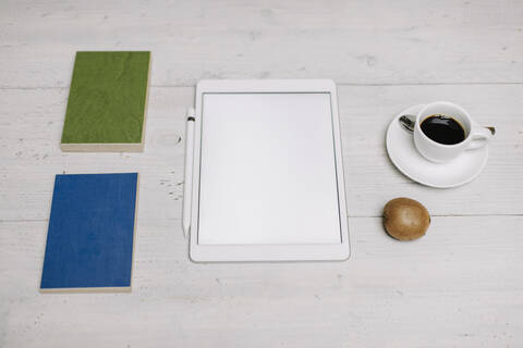 Tablet, Tasse Kaffee, Kiwi und Proben auf Holzoberfläche, lizenzfreies Stockfoto