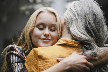 Portrait of adult daughter embracing mother outdoors - GUSF03463