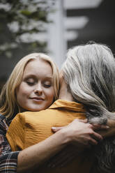 Portrait of adult daughter embracing mother outdoors - GUSF03464