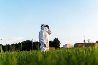 Wissenschaftlerin forscht im Feld und schaut durch ein Fernglas bei Sonnenuntergang - ERRF02773