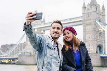 London, Vereinigtes Königreich: Ein Paar, bestehend aus einem Jungen und einem Mädchen, die neben der London Bridge sitzen - DGOF00504