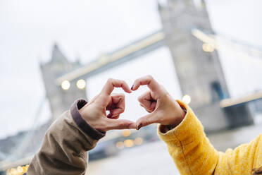 London, United Kingdom, Couple making heart-shaped finger frame - DGOF00507