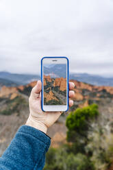 Mann hält Smartphone mit Bild der Mina de Oro Romana, Las Medulas, Kastilien und Leon, Spanien - DGOF00528
