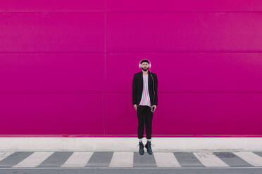 Businessman walking along a pink wall - ERRF02787