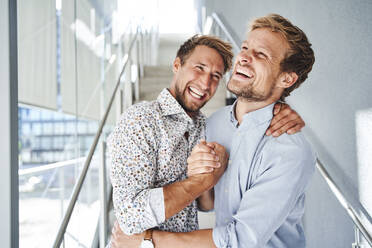 Porträt von zwei glücklichen jungen Geschäftsleuten beim Händeschütteln - PNEF02364