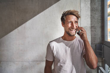 Glücklicher junger Mann mit T-Shirt, der telefoniert - PNEF02382