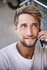 Portrait of young man wearing t-shirt talking on the phone - PNEF02400