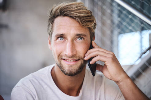 Porträt eines jungen Mannes mit T-Shirt, der telefoniert - PNEF02401