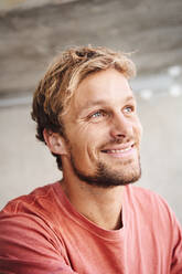 Portrait of smiling young man wearing t-shirt looking up - PNEF02408