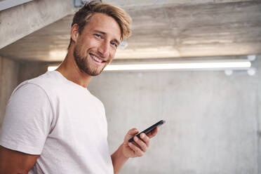 Portrait of attactive young man wearing white t-shirt holding smartphone - PNEF02415