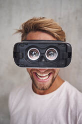 Lachender junger Mann mit Virtual-Reality-Brille - PNEF02418