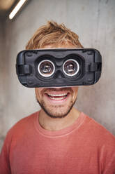 Laughing man wearing virtual reality goggles - PNEF02419