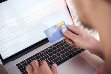 Man using laptop and holding credit card, close-up - PNEF02425