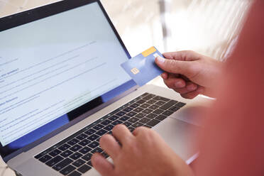 Man using laptop and holding credit card, close-up - PNEF02426