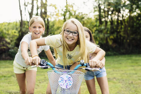 Glückliche Mädchen fahren Fahrrad im Garten, lizenzfreies Stockfoto