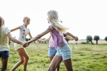 Happy girls dancing on a field together - SODF00633