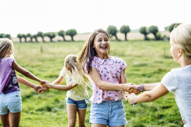 Happy girls dancing on a field together - SODF00635