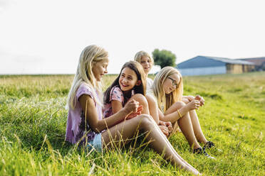 Girls sitting on a field in the countryside - SODF00639