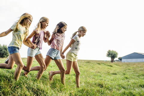 Happy girls running on a field in the countryside stock photo