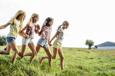 Happy girls running on a field in the countryside - SODF00641