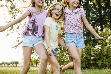 Happy girls running on a field in the countryside - SODF00642