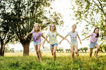 Happy girls running on a field in the countryside - SODF00643