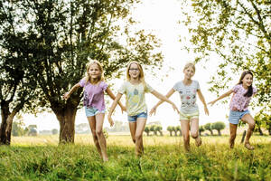 Glückliche Mädchen, die auf einem Feld auf dem Lande laufen - SODF00643
