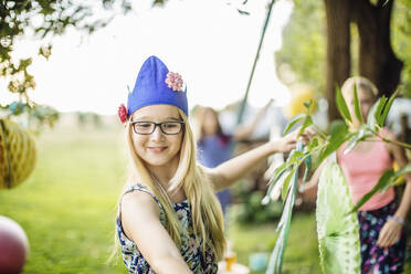 Mädchen mit Partyhut schmückt den Garten für eine Geburtstagsfeier - SODF00656