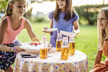 Glückliche Mädchen feiern eine Geburtstagsparty im Freien - SODF00660