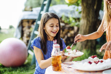 Mädchen erhält ein Stück Kuchen auf einer Geburtstagsfeier im Freien - SODF00670