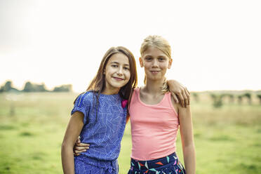 Porträt von zwei lächelnden Mädchen, die sich auf einem Feld umarmen - SODF00681
