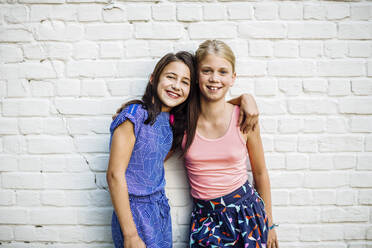 Portrait of two happy girls embracing at a wall - SODF00682