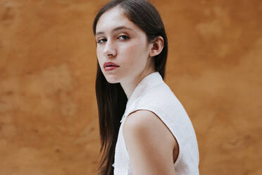 Portrait of female teenager in front of a brown wall - TCEF00227