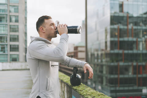 Mann, der eine Pause vom Training mit einer Kettlebell in der Stadt macht, Kanada, lizenzfreies Stockfoto