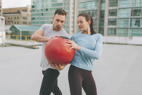 Mann und Frau beim Training mit einem Medizinball in der Stadt, Vancouver, Kanada, lizenzfreies Stockfoto