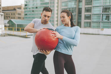 Mann und Frau beim Training mit einem Medizinball in der Stadt, Vancouver, Kanada - CMSF00107