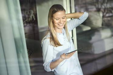 Lächelnde blonde junge Frau mit Tablet - PNEF02429