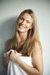 Portrait of happy young woman wrapped in a towel - PNEF02439