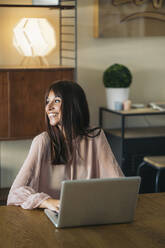 Lächelnde junge Frau, die zu Hause einen Laptop benutzt - MPPF00543