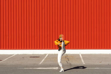 Young woman dancing in front of a red wall - ERRF02828