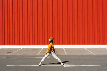 Junge Frau tanzt vor einer roten Wand - ERRF02833