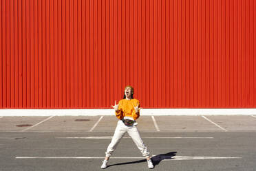 Young woman screaming in front of a red wall - ERRF02836