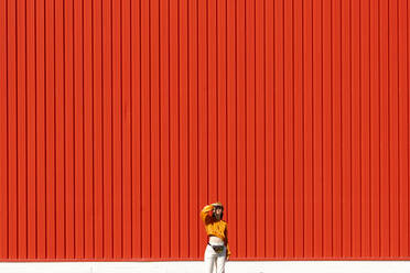 Young woman standing in front of a red wall - ERRF02837