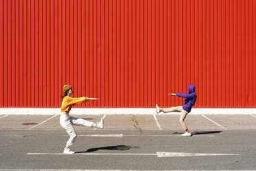 Junger Mann und Frau spielen vor einer roten Wand - ERRF02864