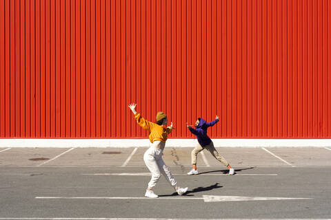 Young man and woman performing in front of a red wall stock photo