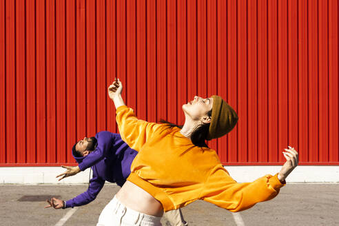 Young man and woman performing in front of a red wall - ERRF02869