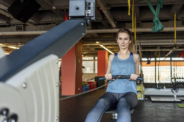 Young woman exercising in gym with rowing machine - VPIF02053