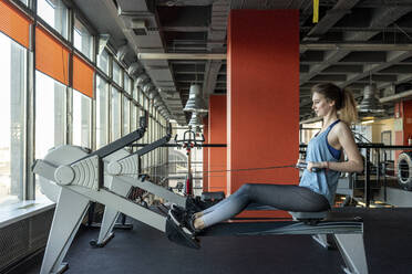 Junge Frau beim Training im Fitnessstudio mit Rudergerät - VPIF02054