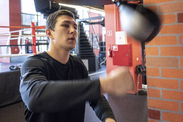 Young man exercising at punch bag in boxing club - VPIF02065